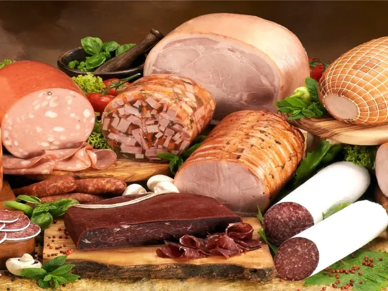 Hams, salamis and sausages laid out on a wooden board