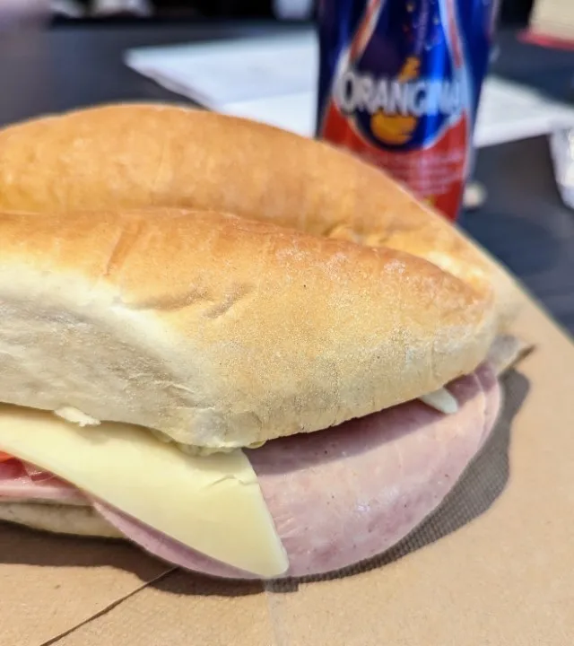 A sandwich on a soft white bun with sliced ham and cheese