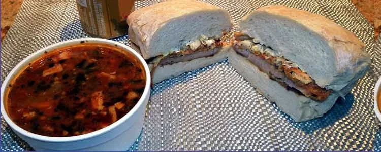 A bowl of soup beside a sandwich cut in half