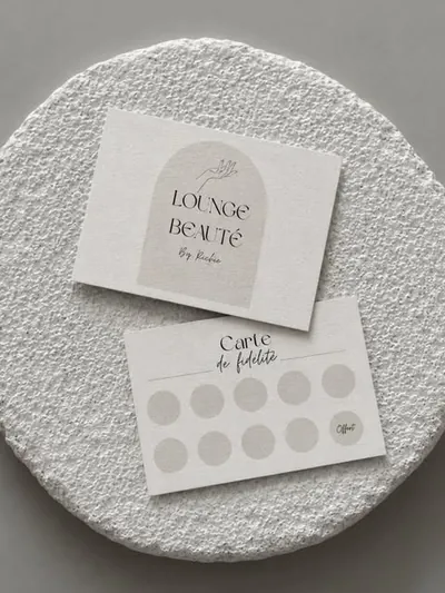 Les cartes Lounge beauté by Richie posées sur un socle de plâtre : la carte au logo en arche et la carte de fidélité.