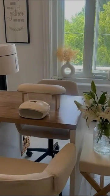Le studio en plein jour : table de manucure en bois, fauteuils crème, lys blancs près de la fenêtre.