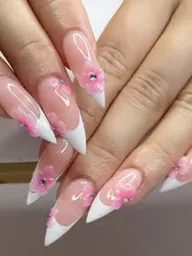 Ongles stiletto nude aux pointes blanches et petites fleurs roses.