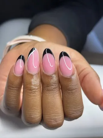 Ongles en amande rose aux pointes noires traversées d’une fine ligne blanche.