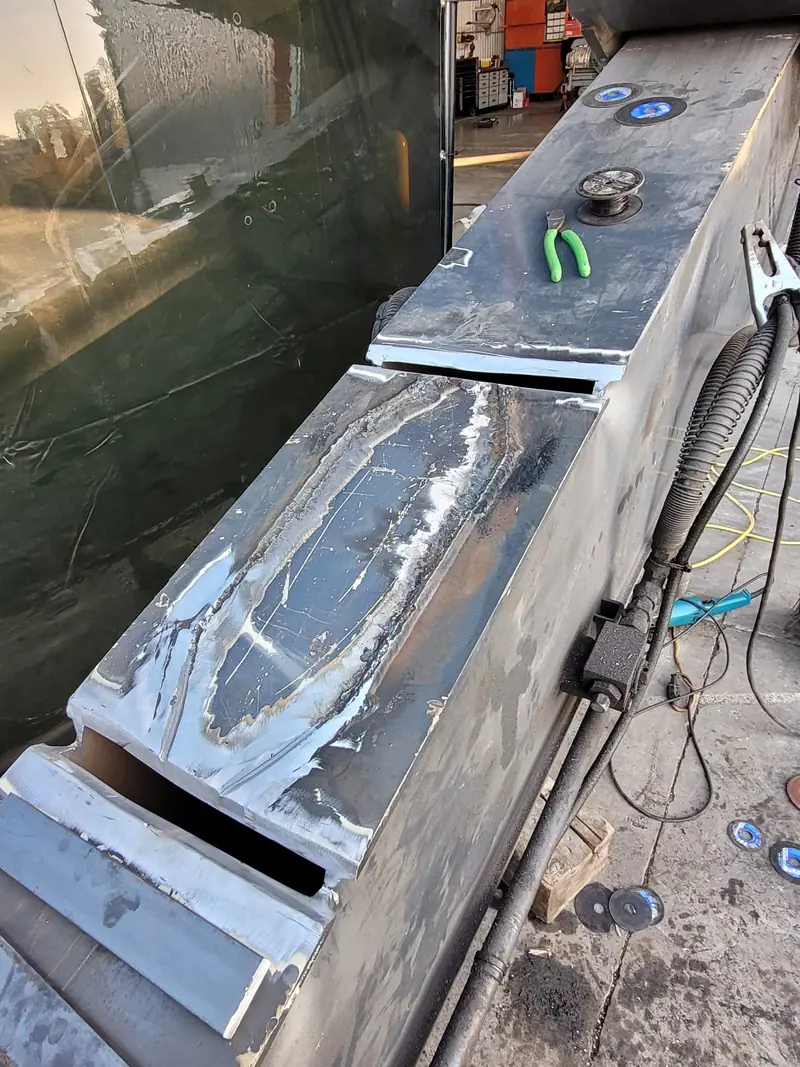 Excavator boom on the shop floor with the cracked areas cut out to bare metal